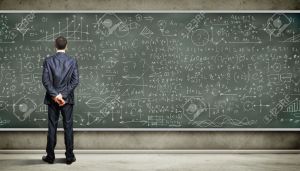 18183109-Business-person-standing-against-the-blackboard-with-a-lot-of--Stock-Photo